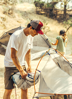 Discover our UV protective sun blocking headwear A young man wearing columbia putting up a tent